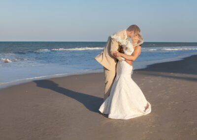 Bride and groom kiss on beach