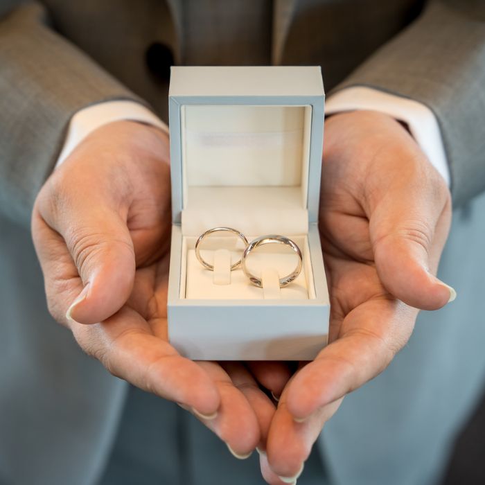 groom holding wedding rings